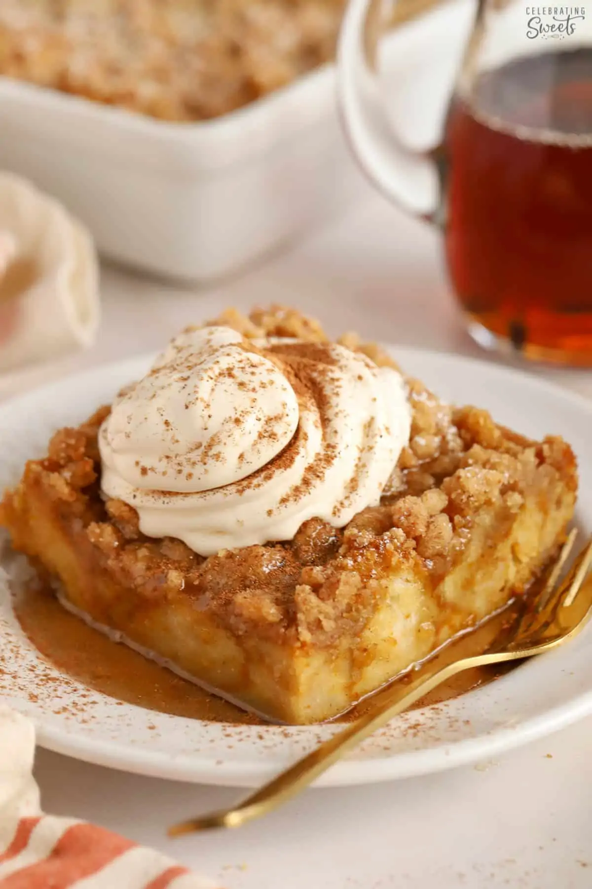 Pumpkin french toast casserole on a white plate topped with whipped cream and cinnamon