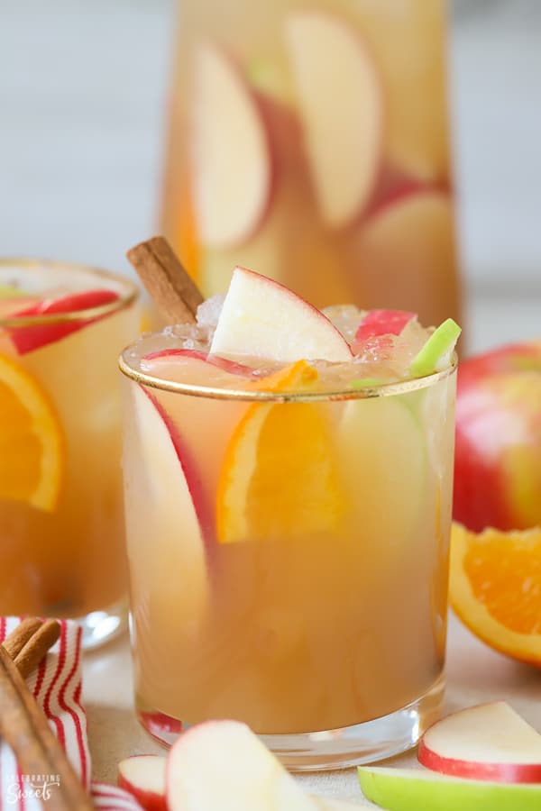 Sangria in a glass garnished with sliced apples, oranges, and cinnamon sticks. 