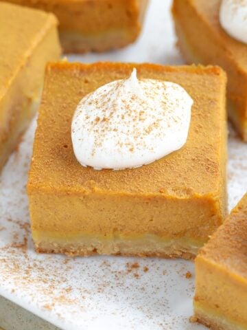 Square slice of pumpkin pie topped with whipped cream.