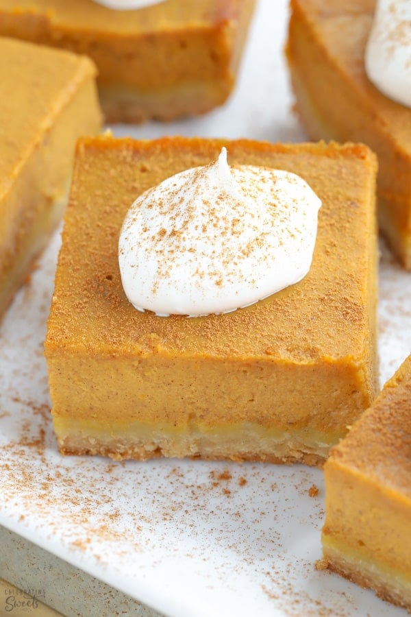 Square slice of pumpkin pie topped with whipped cream.