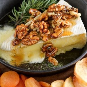 Wedge of brie cheese topped with walnuts and honey.