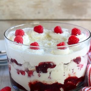 Trifle dish with cake, whipped cream, jam and raspberries.