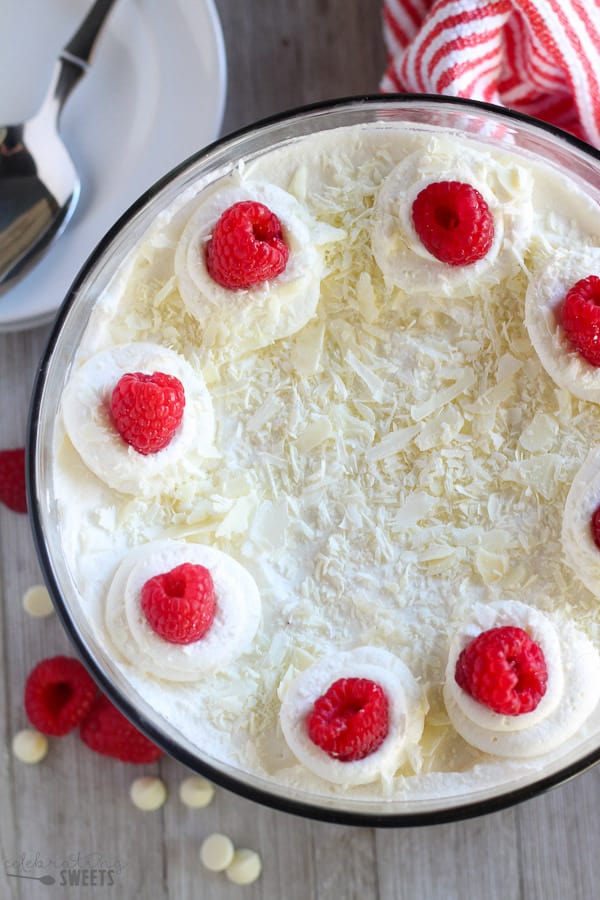 Whipped cream and raspberries on top of a trifle dish.