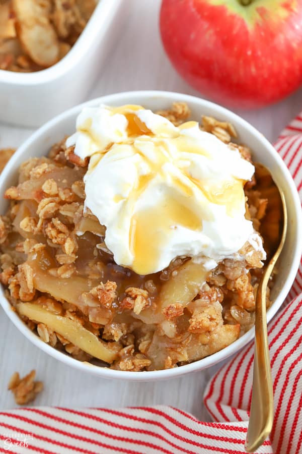 Apple crisp in a white bowl next to a red and white striped napkin