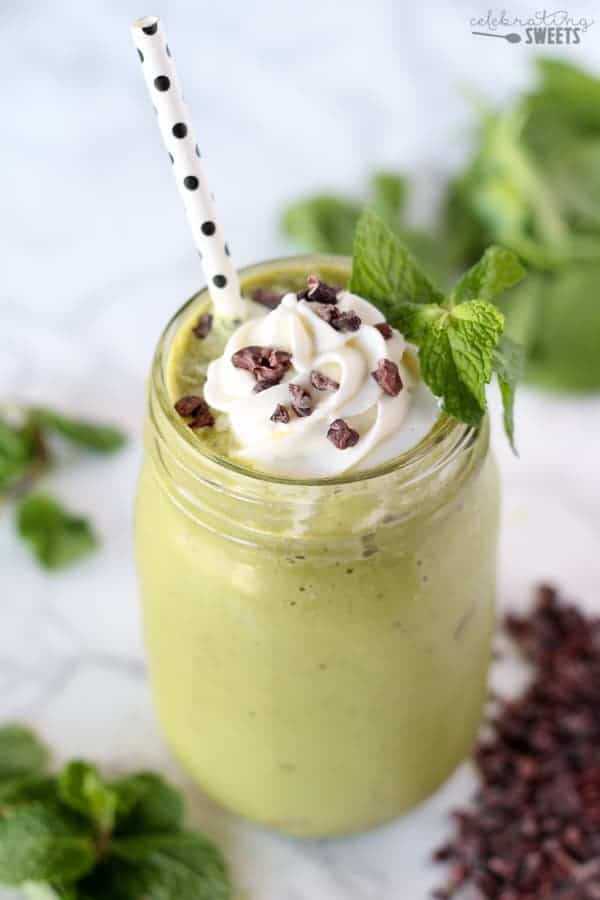 Mint chocolate chip smoothie in a glass topped with whipped cream.