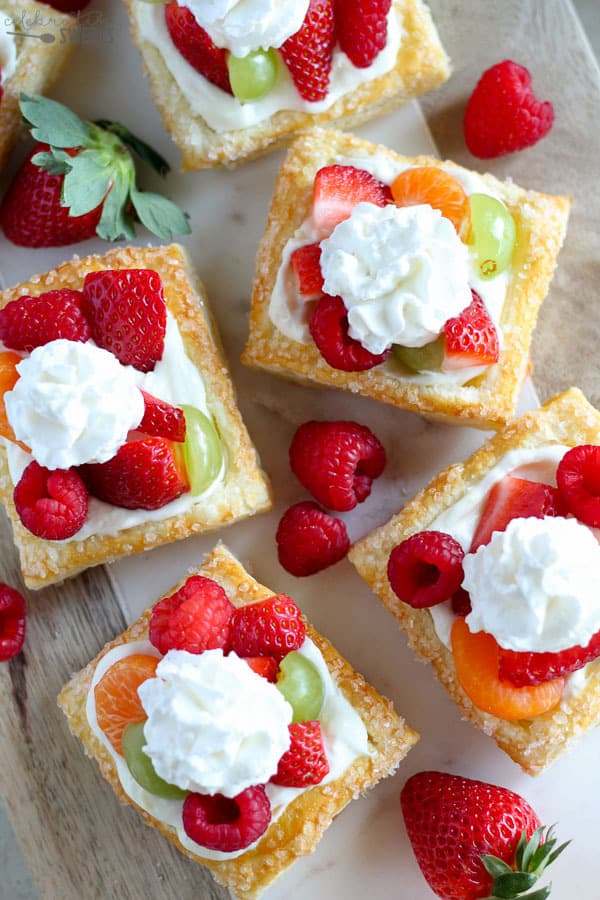 Mini Cream Cheese Fruit Tarts- A puff pastry tart shell filled with a no-bake lemon cream cheese filling and topped with fresh fruit and whipped cream.