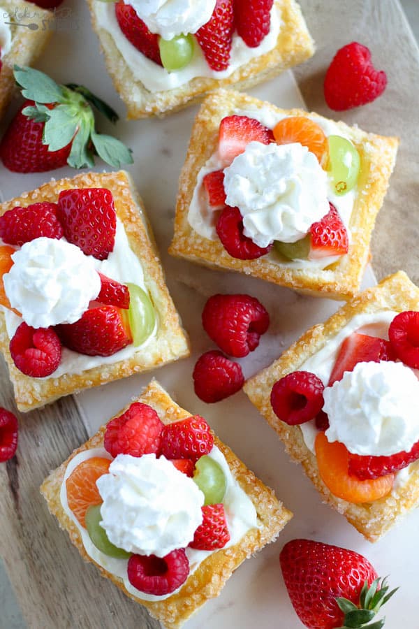 mini Cream Cheese Fruit Tarts - skorupa tarty z ciasta francuskiego wypełniona nadzieniem z serem cytrynowym bez pieczenia i zwieńczona świeżymi owocami i bitą śmietaną.