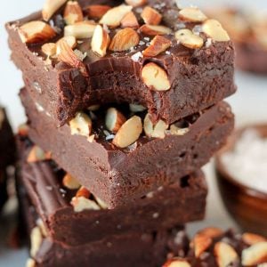 Stack of brownies topped with frosting and almonds.