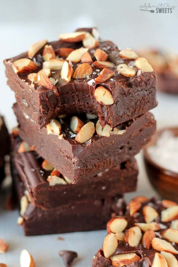Stack of brownies topped with frosting and almonds.