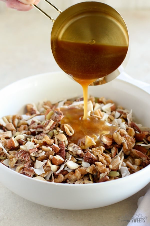 Honey being poured onto nuts and coconut.