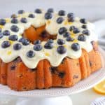 Lemon blueberry bundt cake topped with cream cheese frosting and fresh blueberries.