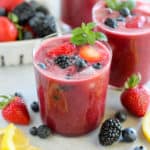 Glass of berry agua fresca topped with fresh berries and mint