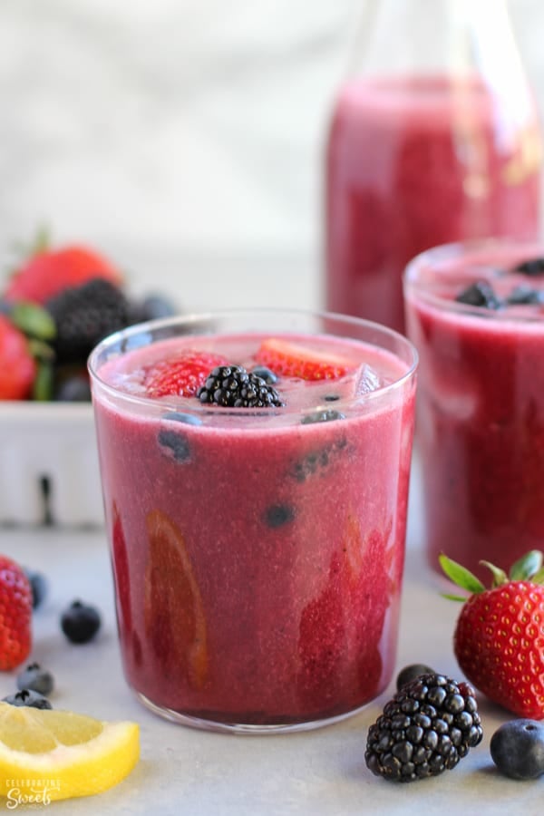 Glass of berry agua fresca topped with fresh berries.