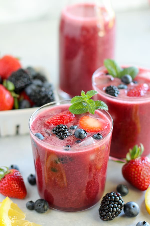 Glass of berry agua fresca topped with fresh berries and mint.
