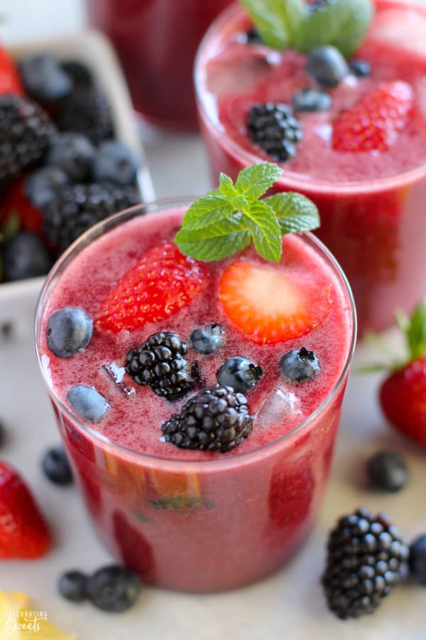 Glass of berry agua fresca topped with fresh berries and mint. 