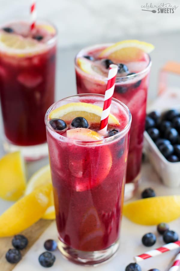 Blueberry lemonade in a glass with a red and white striped straw. 