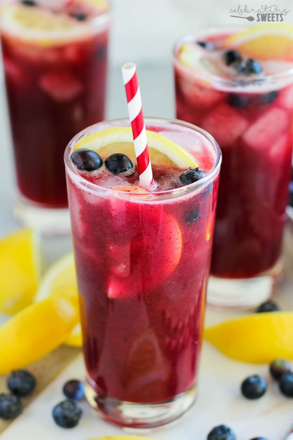 Blueberry lemonade in a glass with a red and white striped straw. 