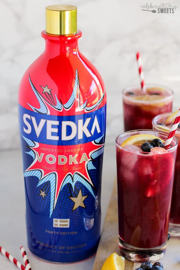 Blueberry lemonade in a glass with a red and white striped straw. 