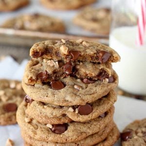 Stack of chocolate chip cookies with milk in the background.