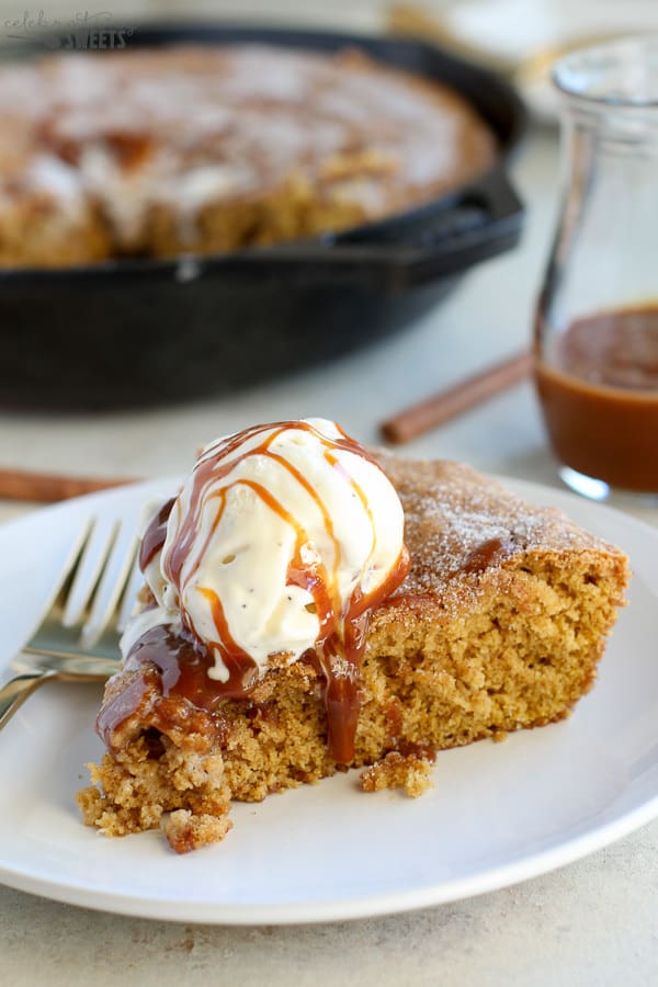 Slice of skillet cookie topped with ice cream and caramel sauce.