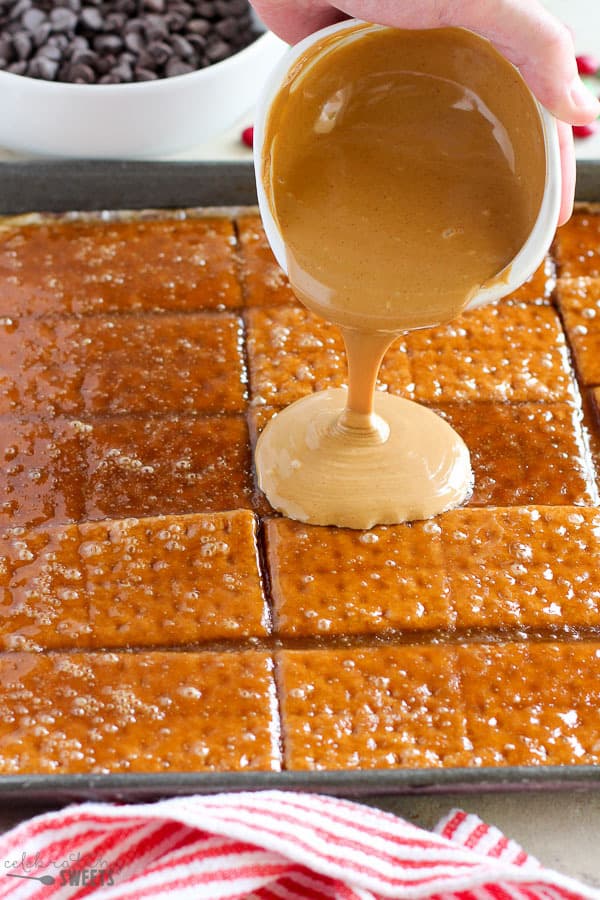 Pouring peanut butter on graham cracker toffee bark.