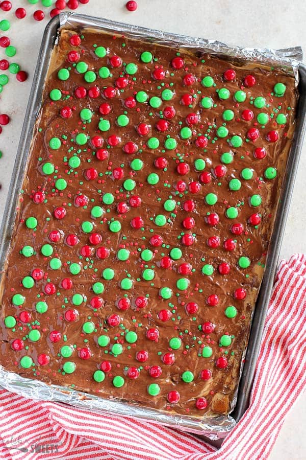 Overhead photo of a sheet pan of toffee bark topped with red and green M&M's and sprinkles