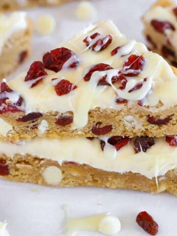 Two blondies topped with frosting and dried cranberries.