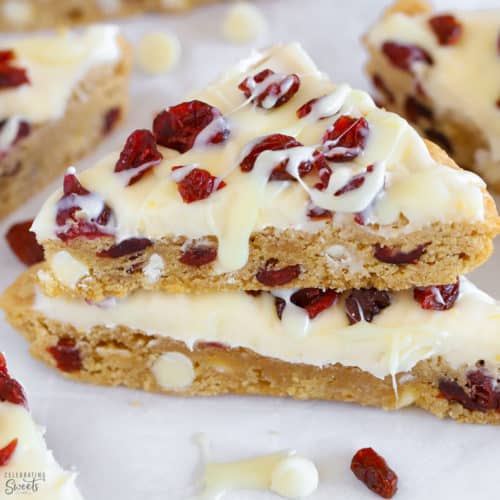 Two blondies topped with frosting and dried cranberries.