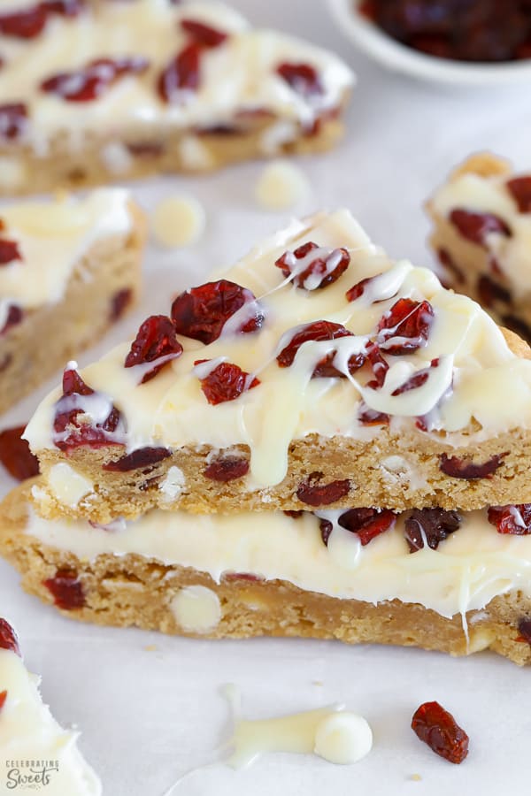 Two blondies topped with frosting and dried cranberries.
