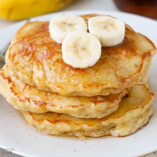 Stack of three banana pancakes on a white plate.