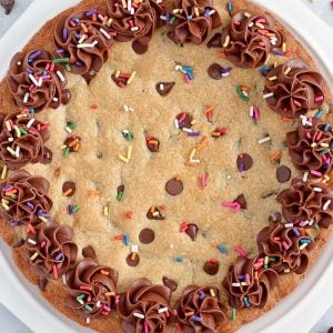 Giant chocolate chip cookie decorated with chocolate frosting and sprinkles.