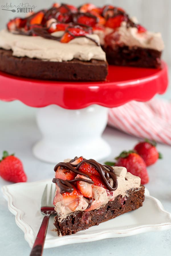 Slice of brownie with strawberries on a white plate.