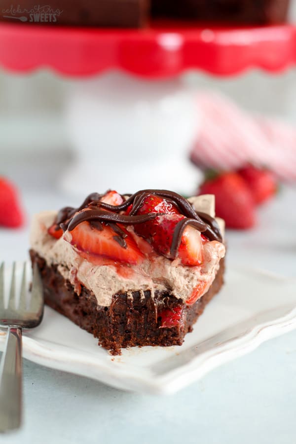 Slice of brownie topped with whipped cream and strawberries.