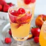 Glass of peach sangria with raspberries and strawberries.