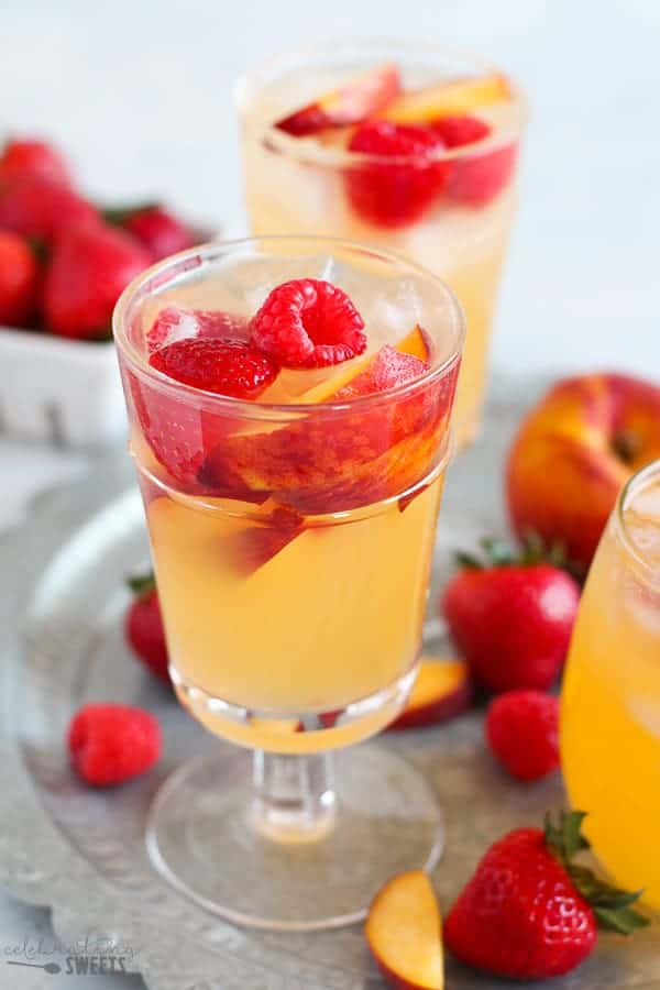 Glass of peach sangria with raspberries and strawberries.