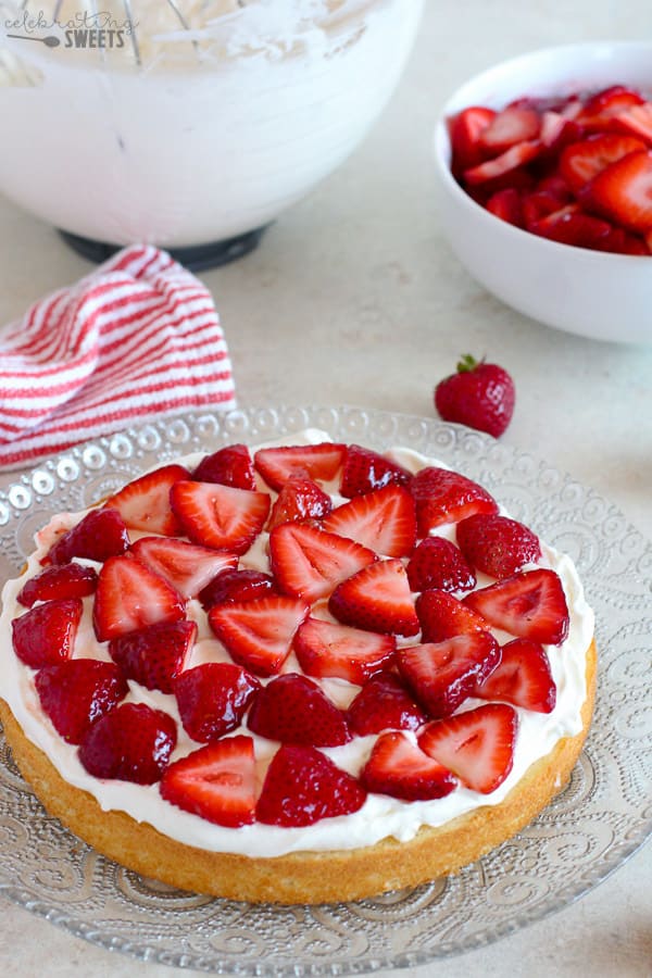 Sliced strawberries and whipped cream on vanilla cake.