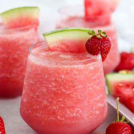 Pink wine slushie garnished with watermelon and strawberry.
