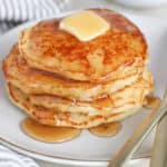 Stack of pancakes topped with butter and syrup.
