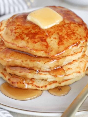 Stack of pancakes topped with butter and syrup.