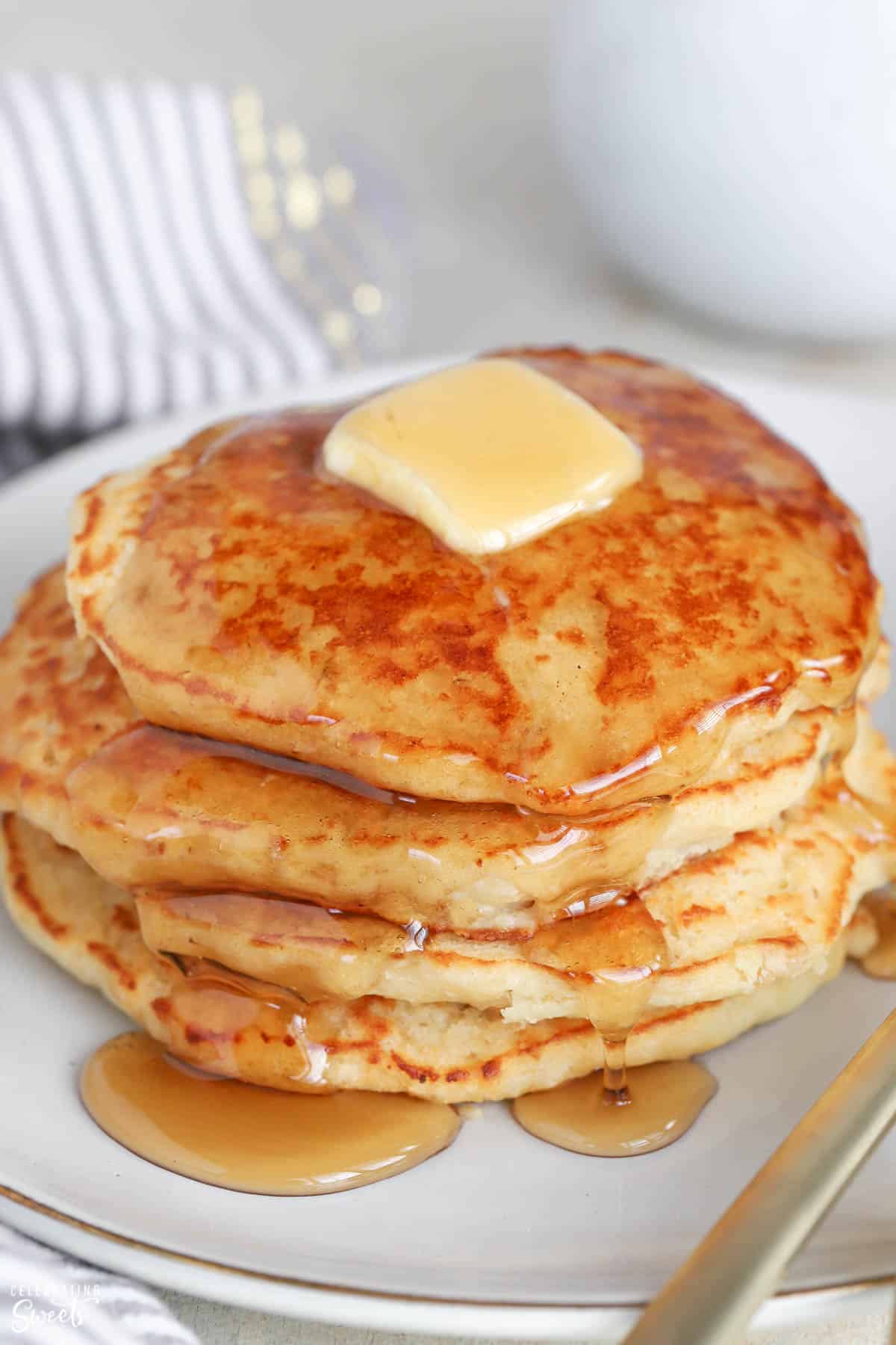 Stack of pancakes topped with butter and syrup.