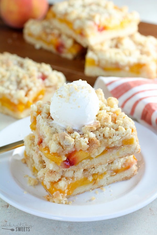 Two peach crumb bars topped with vanilla ice cream.