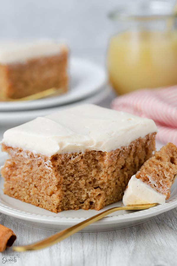 Slice of applesauce cake topped with frosting on a white plate.