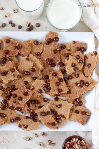 Chocolate Chip Cookie Brittle on a white plate with two glasses of milk.