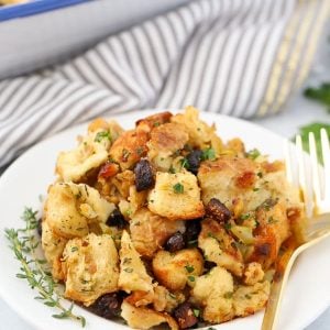 Fig and Sausage Stuffing on a white plate with a gold fork.