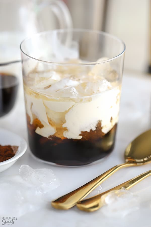 White russian cocktail in a glass with two gold spoons on the side. 