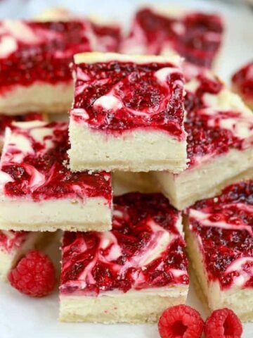 Pile of cheesecake bars swirled with raspberry puree.