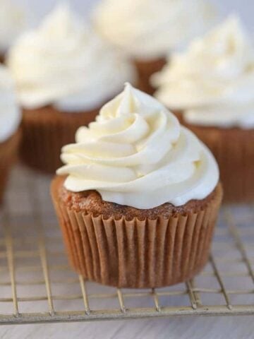 Swirled cream cheese frosting on top of carrot cake.