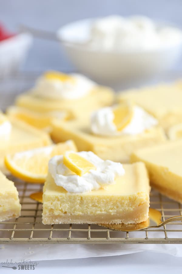 Lemon bars on a rack garnished with whipped cream and a lemon slice.