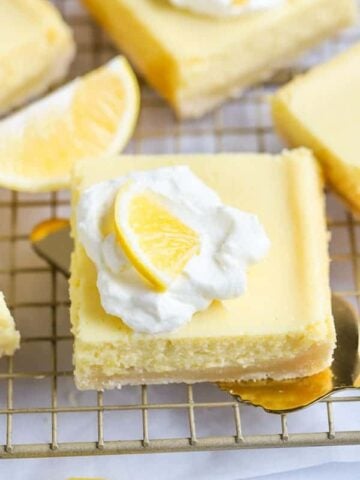 Lemon Bar topped with whipped cream on a spatula.