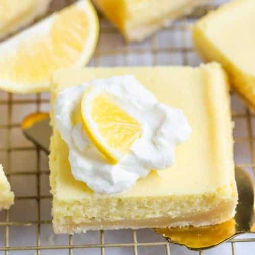 Lemon Bar topped with whipped cream on a spatula.